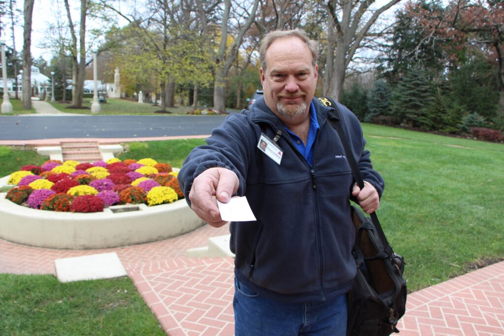 An Althoff employee looking into the camera, smiling and extending a business card to the viewer.