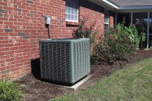 Outdoor central air conditioning unit next to a brick house, indicating central air conditioning repair needs. 